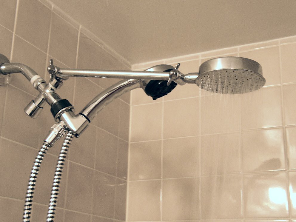 A close view of a chrome shower head and flexible hose, showing the spray face where limescale collects.